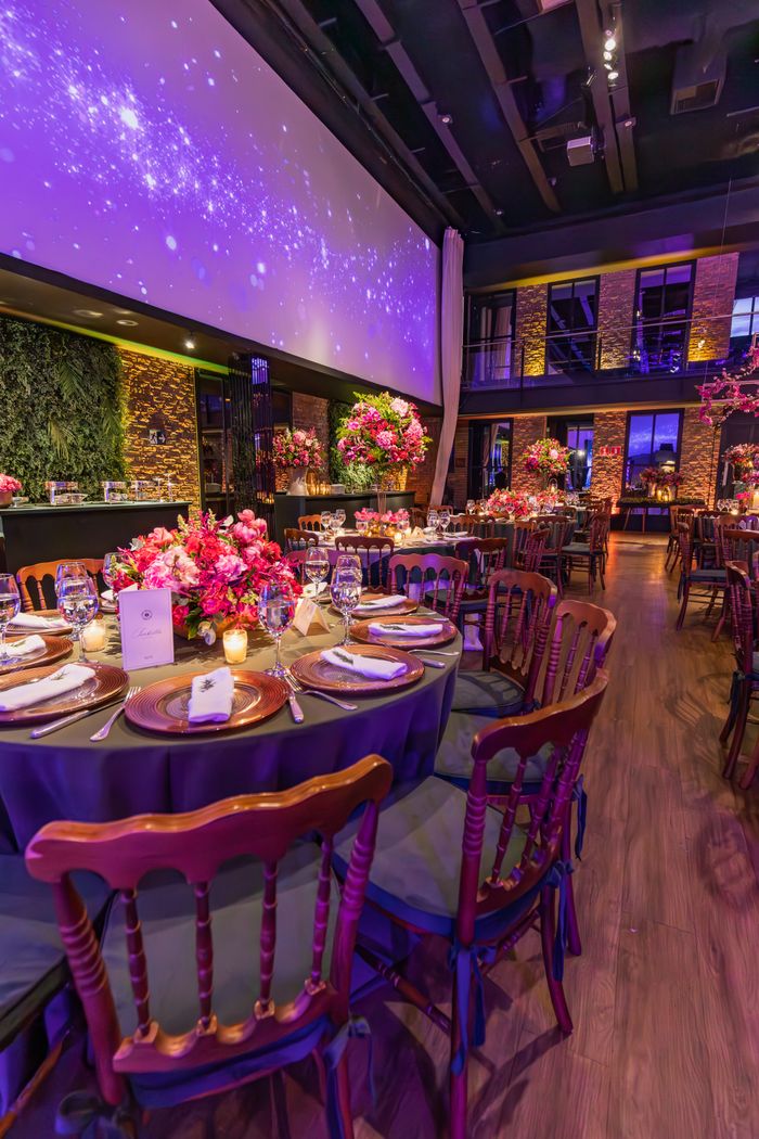 services-03 Lavishly decorated banquet hall with round tables and floral centerpieces under ambient lighting.