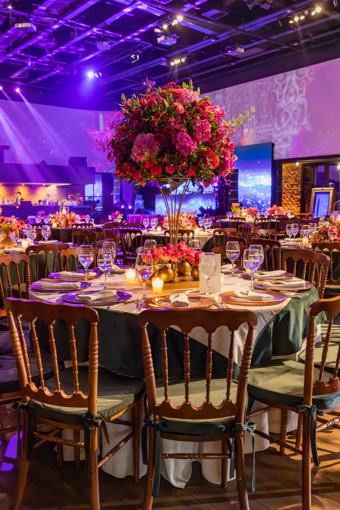 Elegant wedding reception with floral centerpieces and lavish table settings in a grand hall.