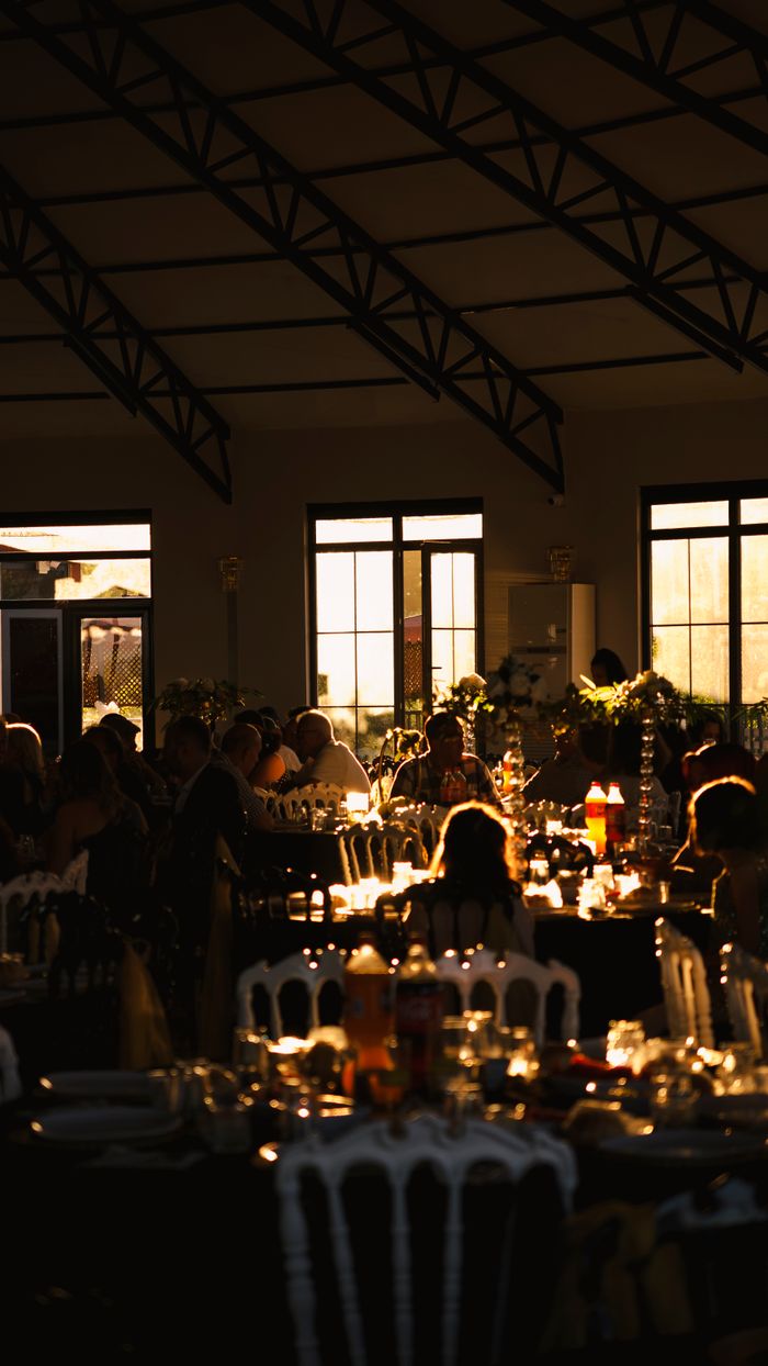 An intimate indoor setting featuring beautifully set tables under warm lighting during a sunset gathering.