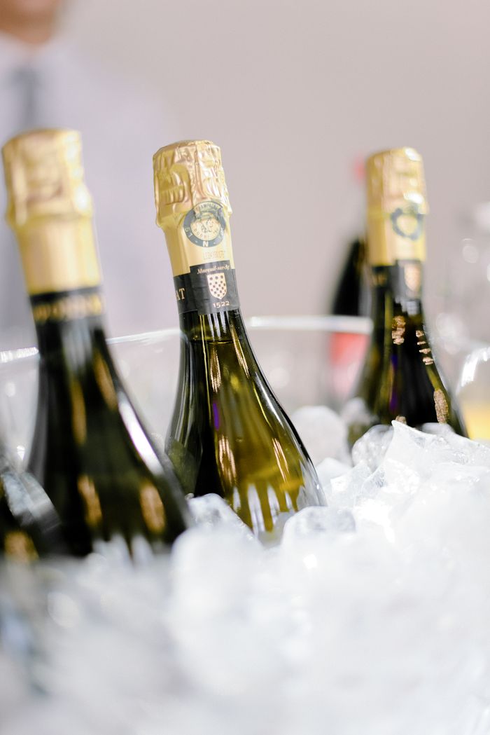 Bottles of sparkling wine placed in metal bucket with ice cubes during banquet